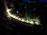 Insulators lit up on edge of flower bed.JPG